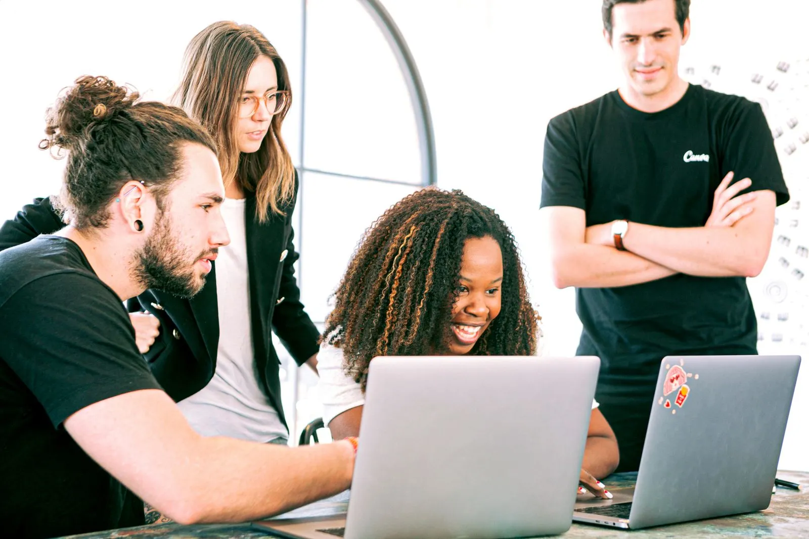 Diverse IT team collaborating around laptops in a modern office
